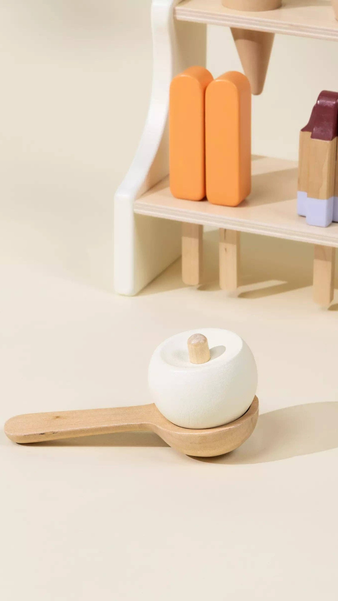 Close-up of creamsicle ice pop and wooden ice cream scoop with a scoop of vanilla ice cream, part of the Wooden Ice Cream Stand playset designed for pretend dessert-making fun and motor skill enhancement.