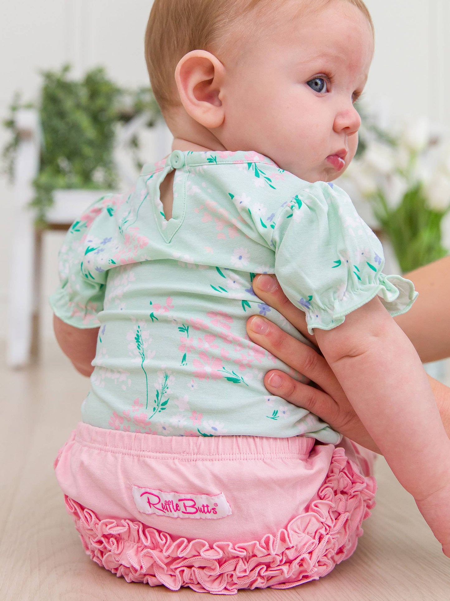 Back view of baby girl wearing mint meadow floral bodysuit with puff sleeves and cozy fit