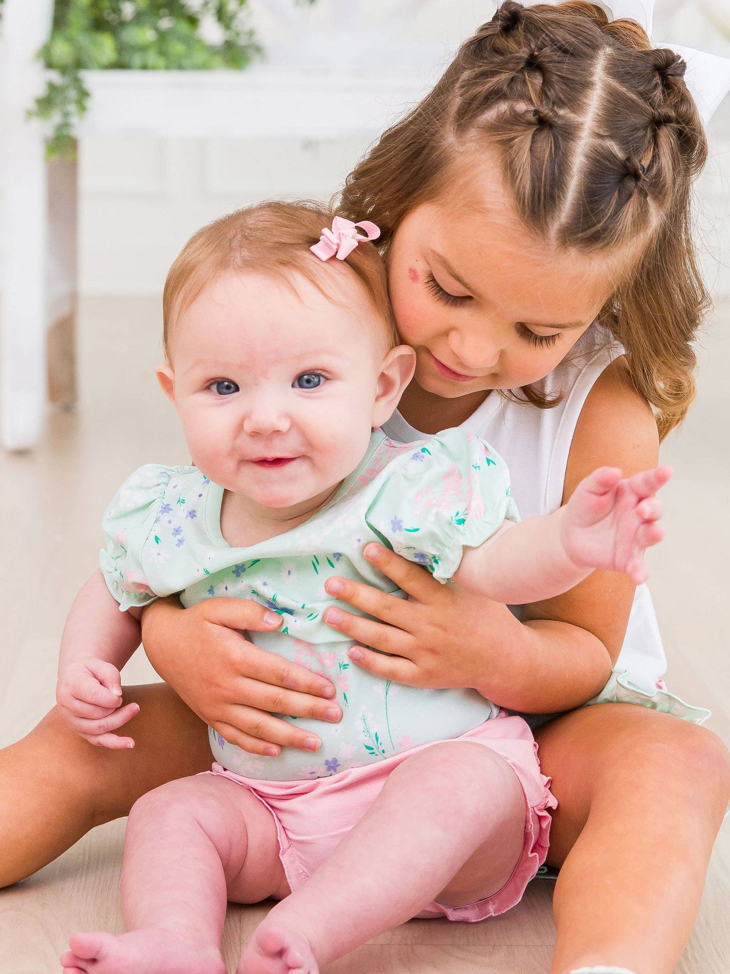 Baby girl wearing mint meadow puff sleeve bodysuit, held by sister in coordinating outfit—perfect for spring photos