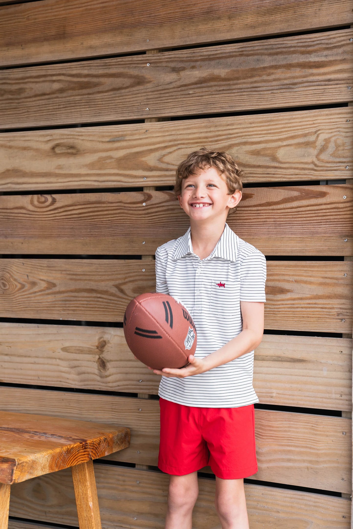 Young boy wearing Boys Marco Performance Polo paired with performance shorts, holding a football, showcasing soft, breathable, and durable play-ready style.