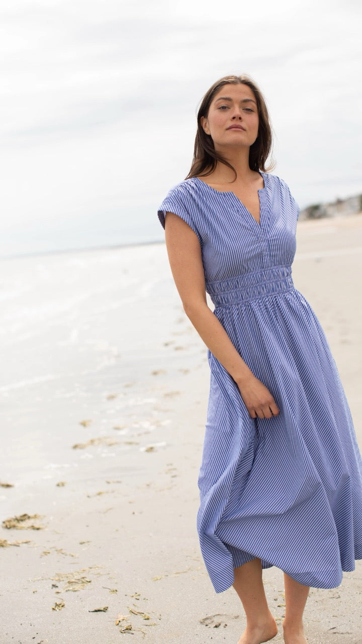 Side view of model walking on the beach at sunset in the Clara Dress, highlighting the roll sleeve detail and relaxed yet elegant silhouette.