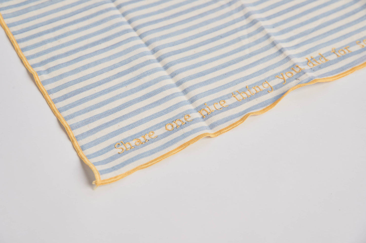 Close-up of a hand-embroidered prompt on one of the conversation napkins, showing fine stitching on chambray fabric