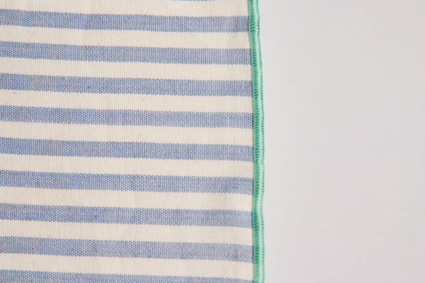 Close-up of the handwoven dinner napkin showing colorful side stitching detail along the edge, highlighting artisan craftsmanship and texture