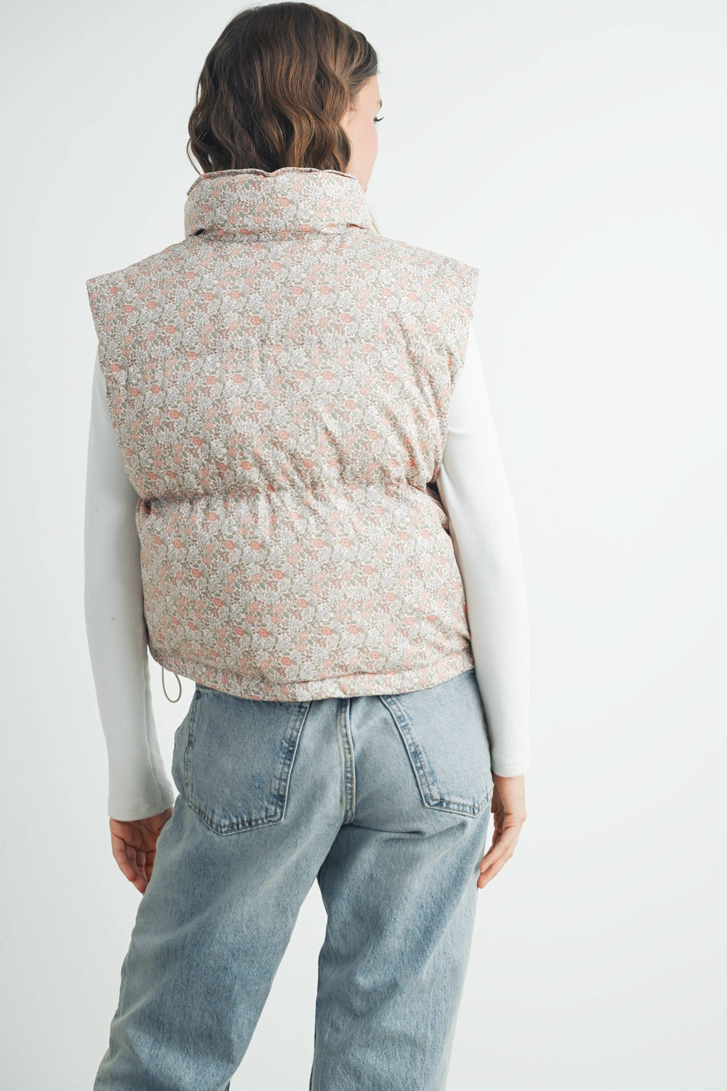 Back view of the Floral High Neck Puffer Vest on model paired with jeans, showcasing full floral pattern and structure of the vest