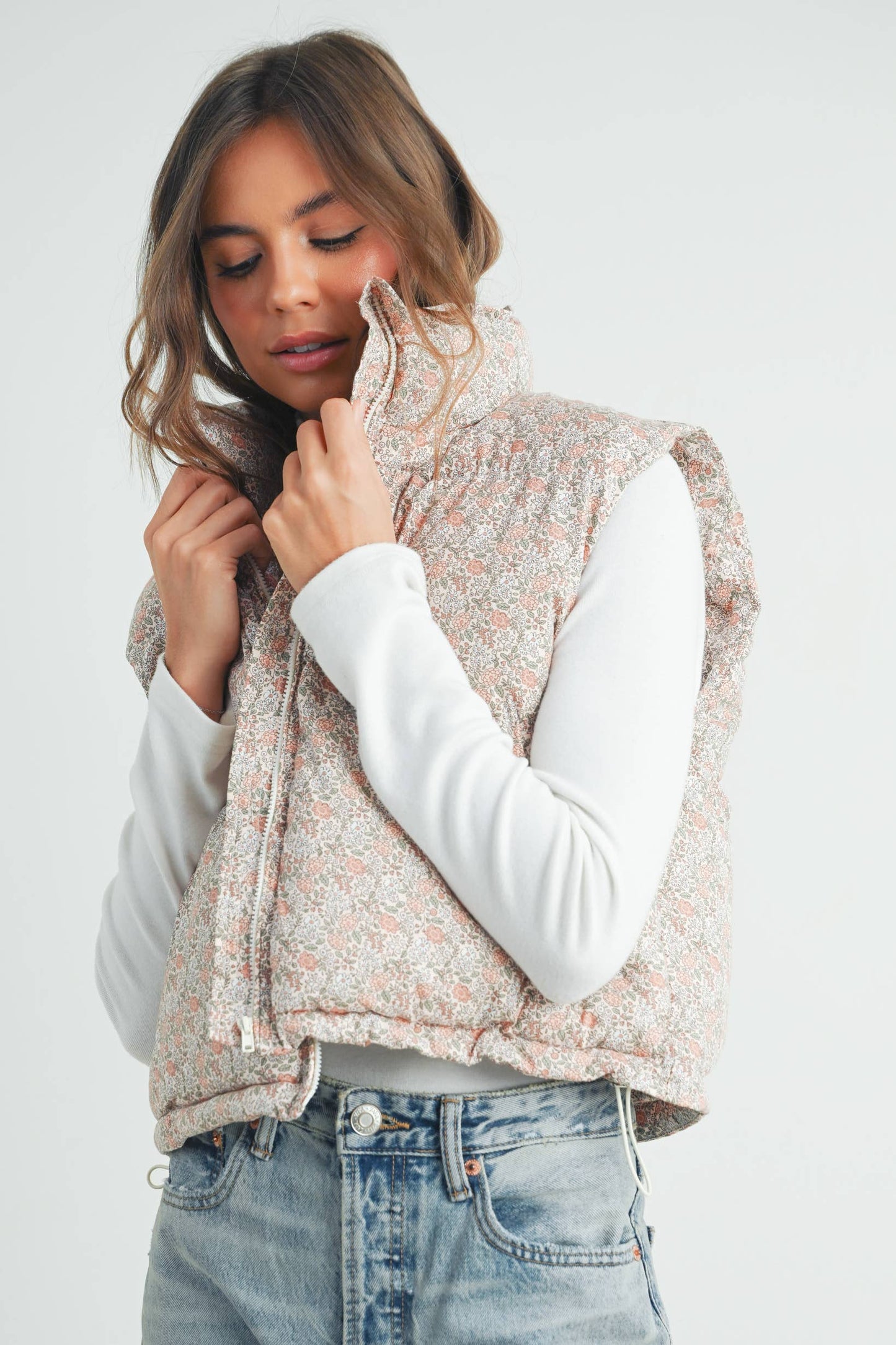 Side view of model wearing the high neck floral puffer vest, showing length and silhouette with casual jeans