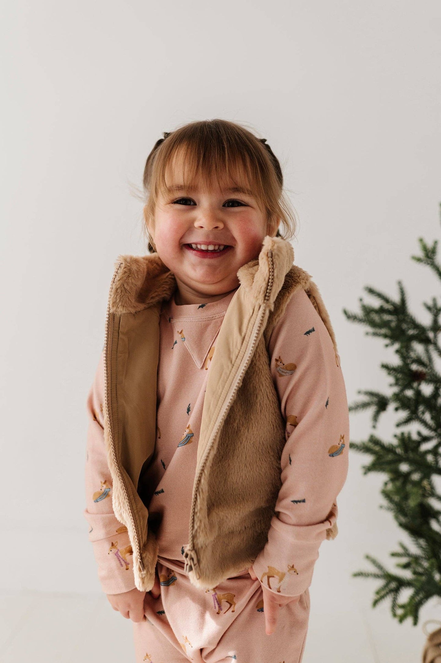 Toddler sitting in studio wearing soft faux fur vest, showing cozy comfort and playful style.