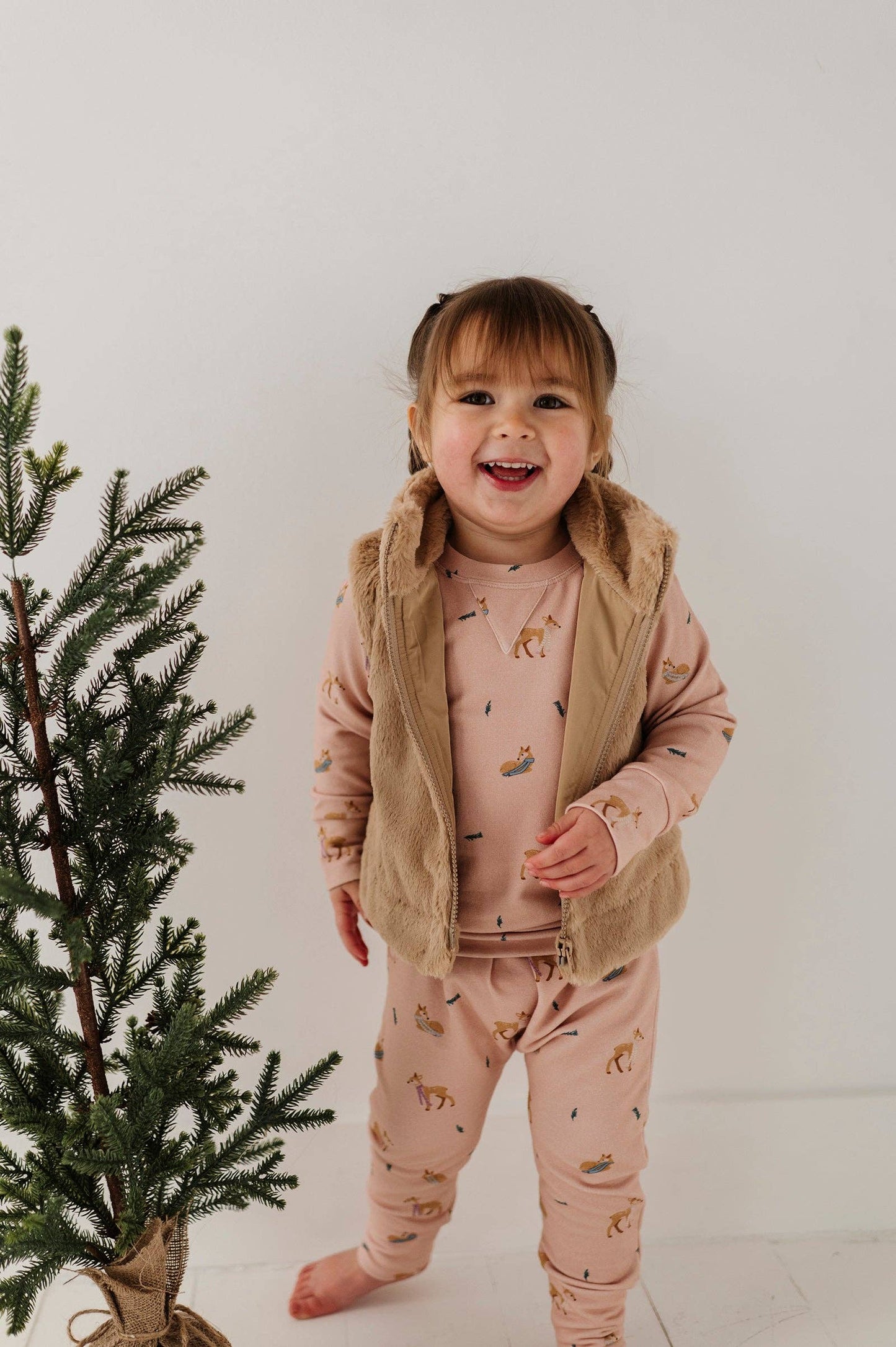 Child modeling faux fur vest, side view, highlighting warm and stylish winter layering for kids.