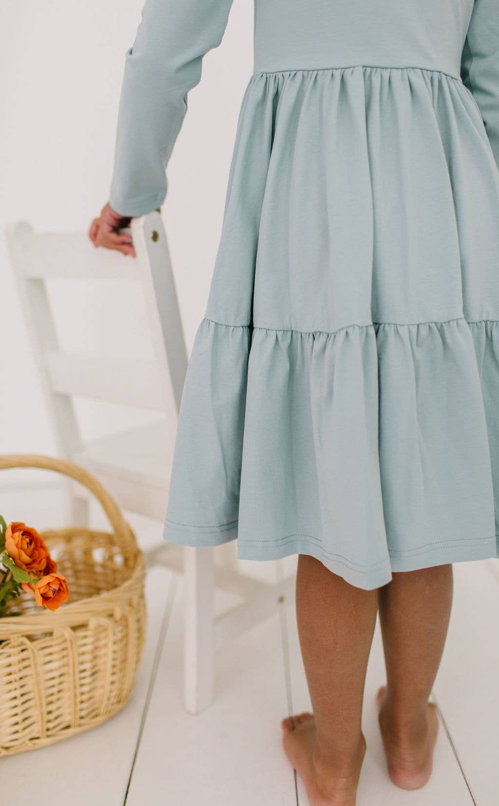 Close-up of the Gwendolyn Ruffle Dress in dusty blue, highlighting the soft fabric and midline ruffle details of the skirt.