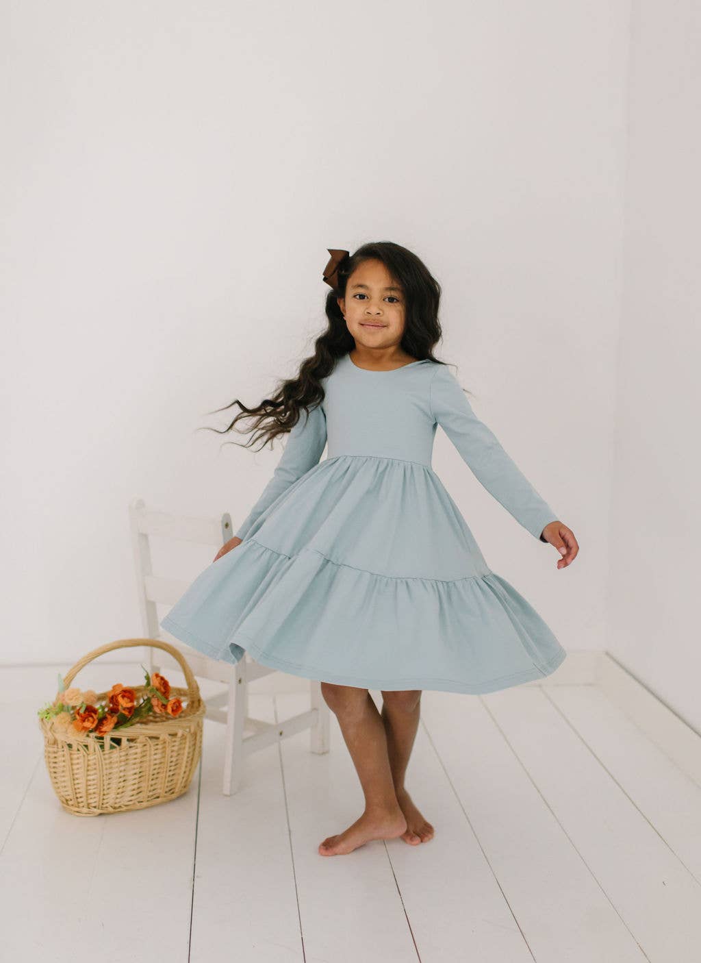 Toddler model twirling in the Gwendolyn Ruffle Dress in dusty blue, showing off the full-circle skirt in motion.