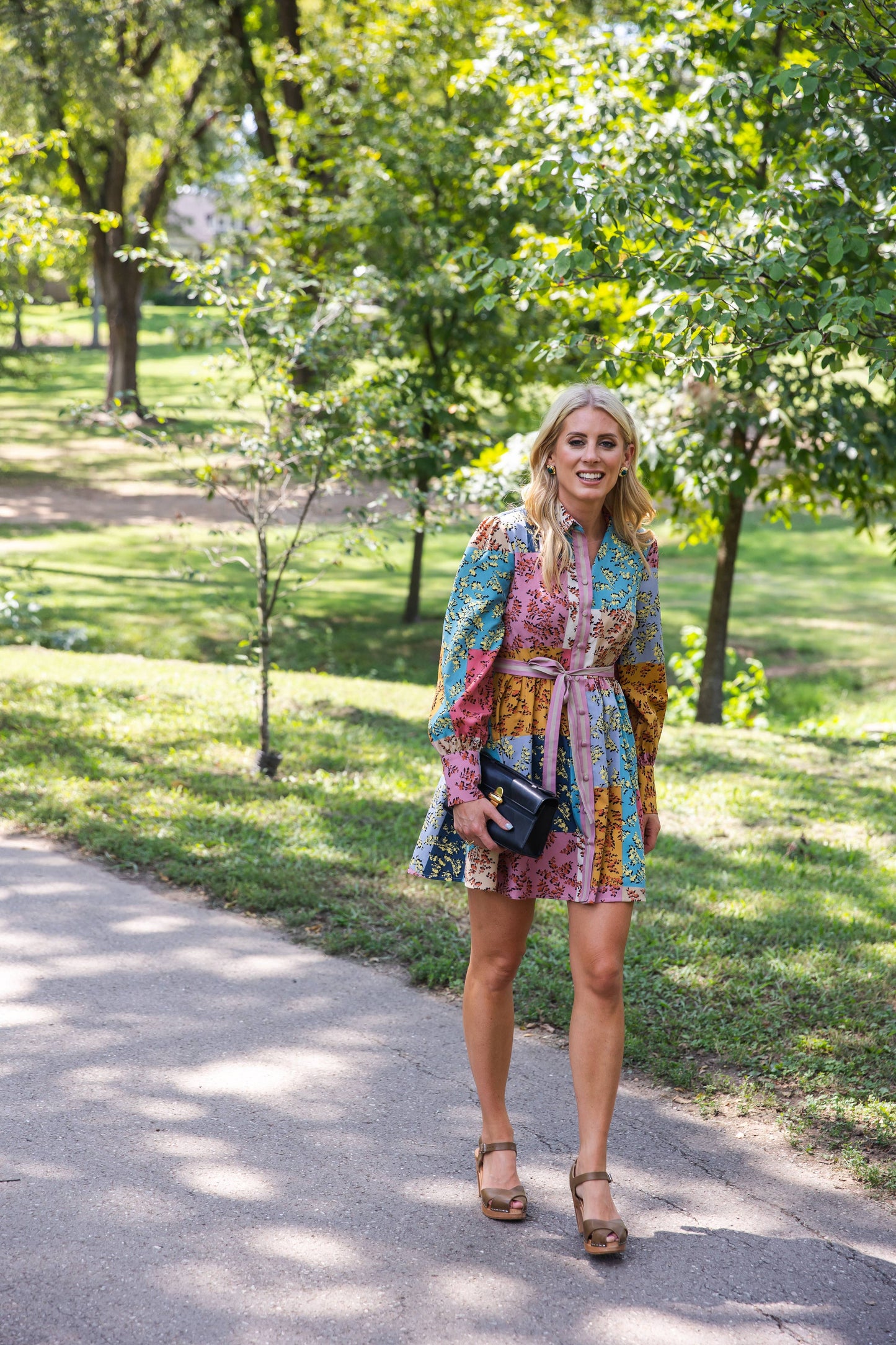 The Jules Dress styled in a lush garden, highlighting its bold patchwork floral print and effortless fit.