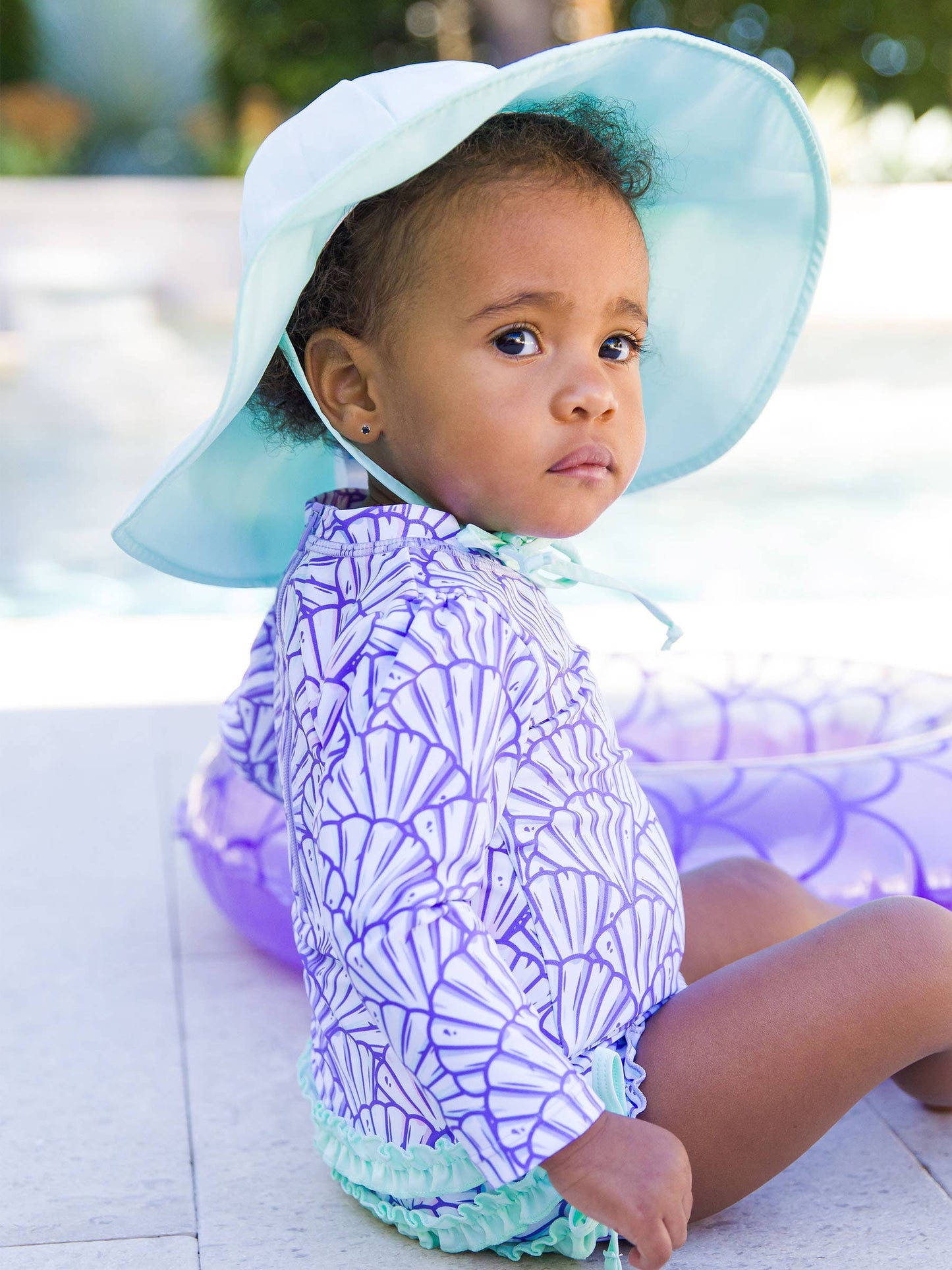 Front view of baby wearing mint sun protective hat with chin straps, styled with matching swimwear