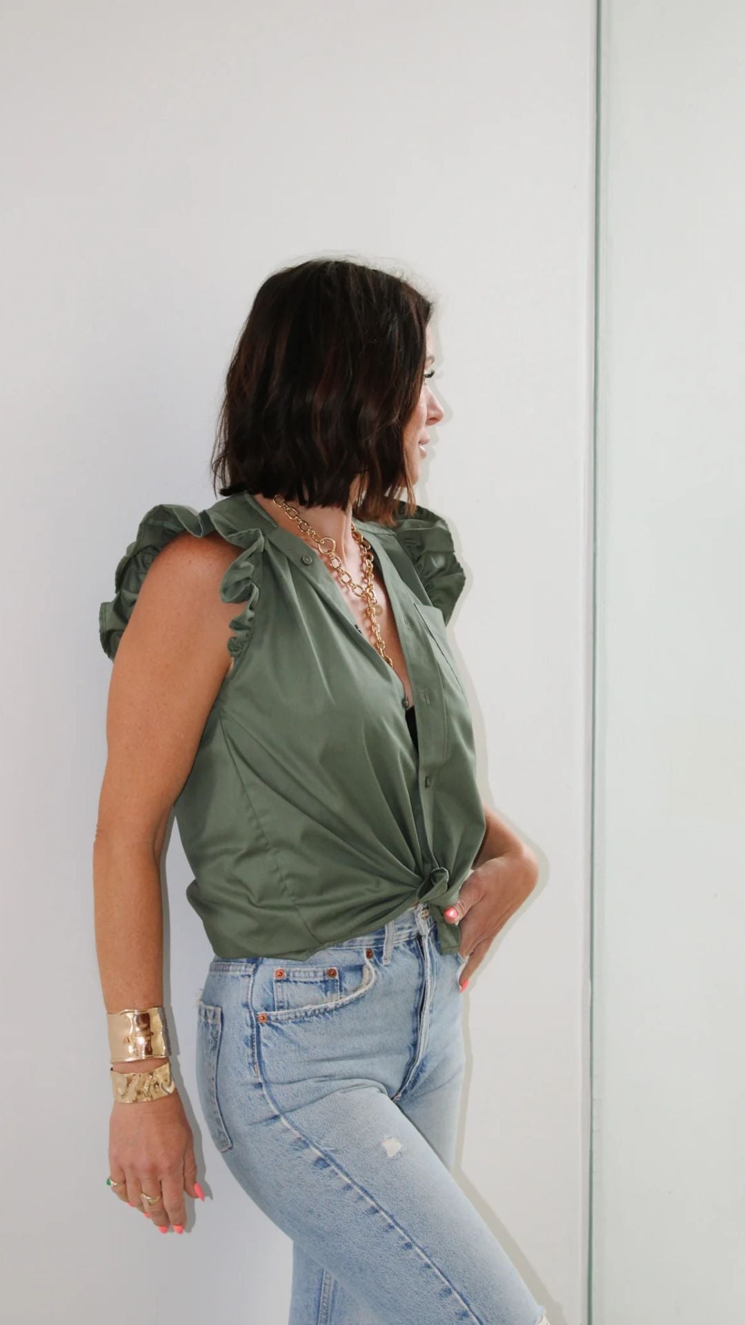 Side profile of designer Kate wearing the Olivia in Olive by KMJ, paired with denim in a studio setting.