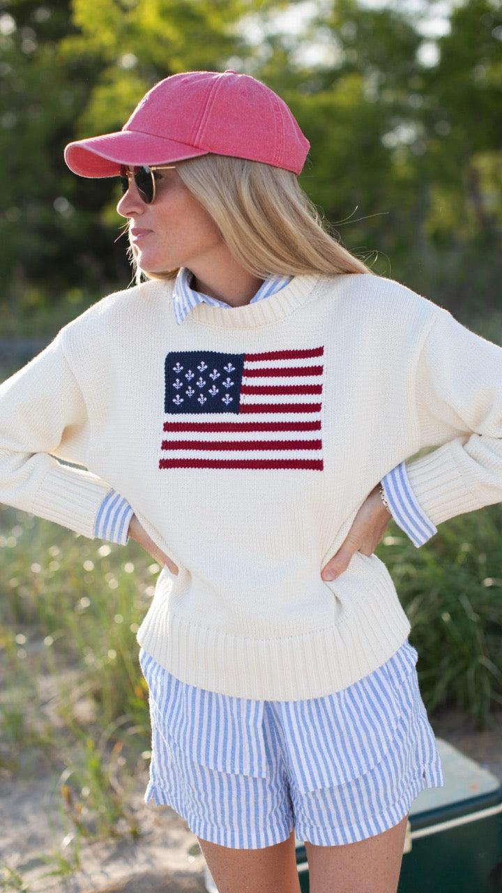 Liz, the designer of Marea, styled in the Flag Sweater with shorts on the beach—effortless summer style.