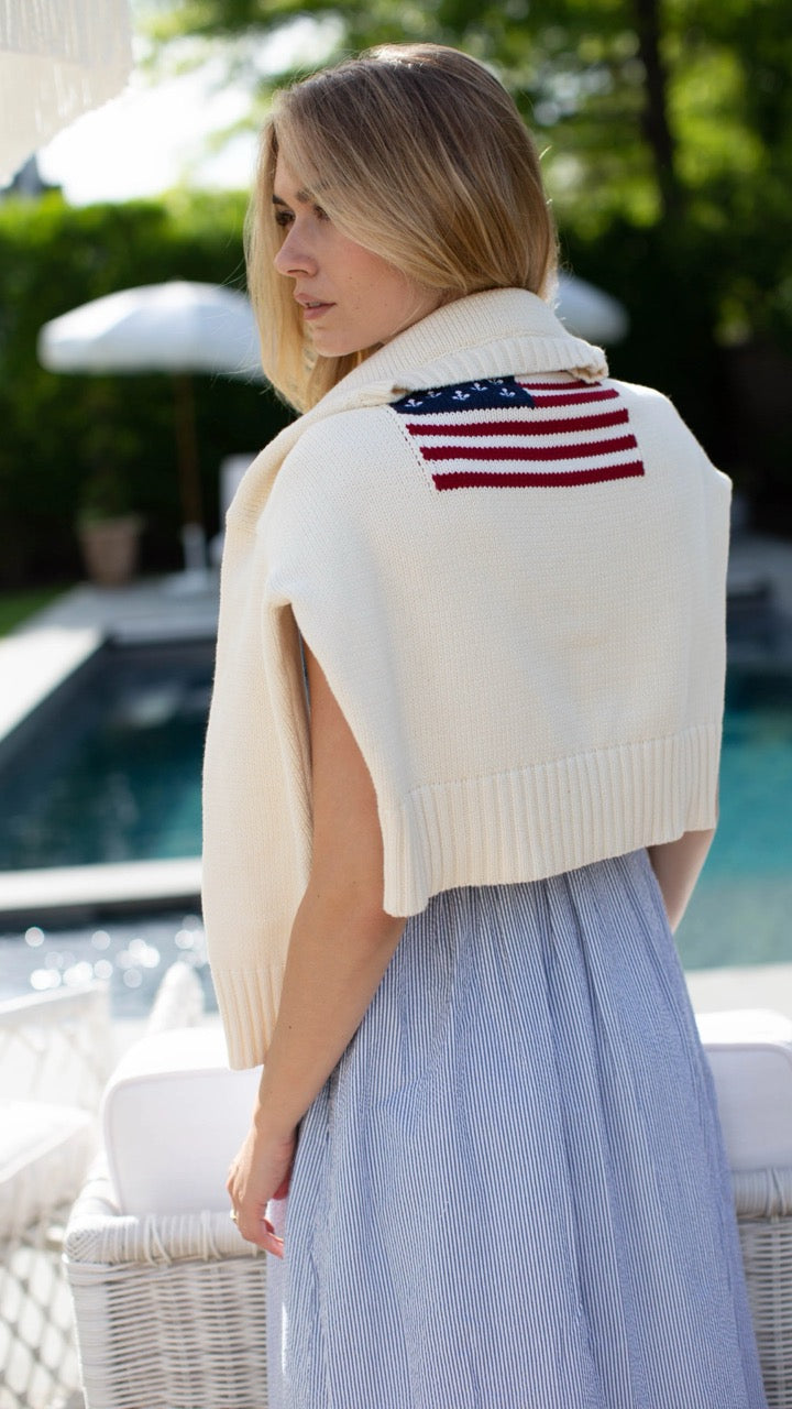 Marea Flag Sweater in ivory, casually draped over the shoulders and paired with the Clara Pinstripe Dress—front view.