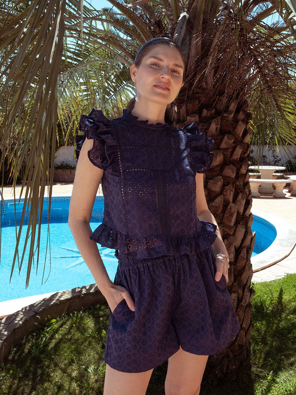 Model wearing navy Olivia shorts and Sasha top in front of a palm tree, styled for a relaxed vacation outfit.