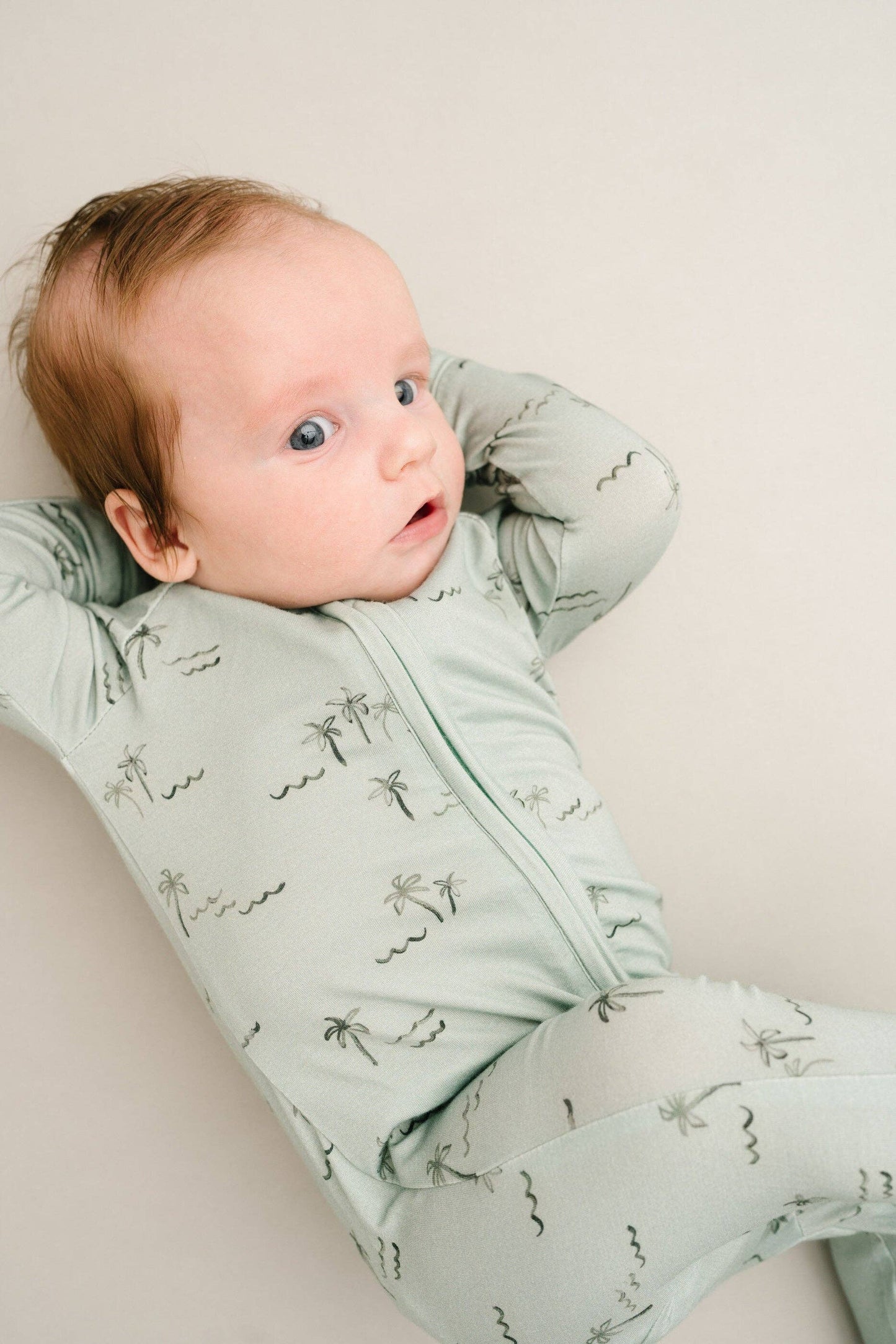 Baby curled up in crib wearing Palm Breeze Bamboo Sleeper, demonstrating cozy comfort.