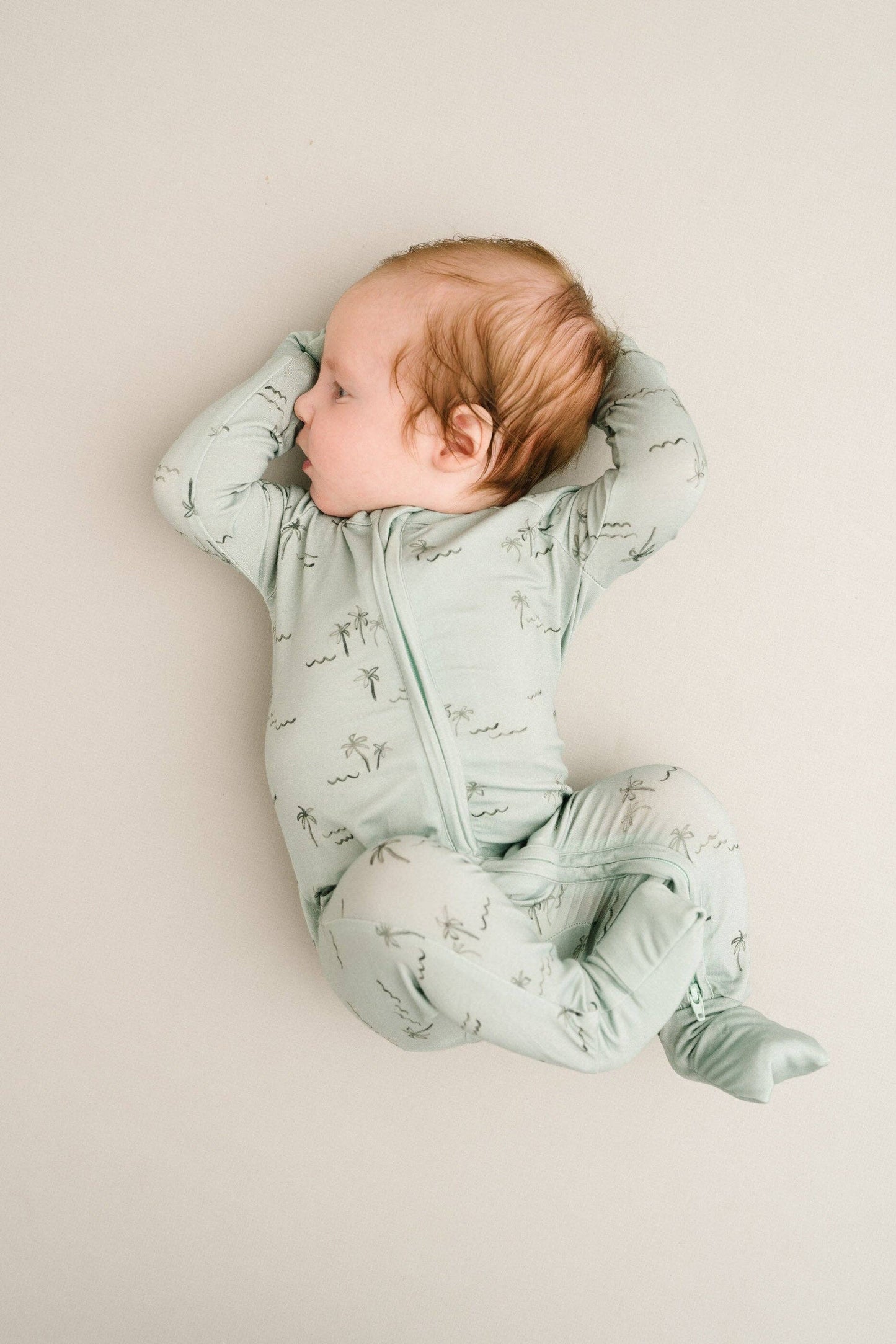 Baby in crib wearing Palm Breeze Bamboo Sleeper with fold-over footies down, highlighting full foot coverage option.