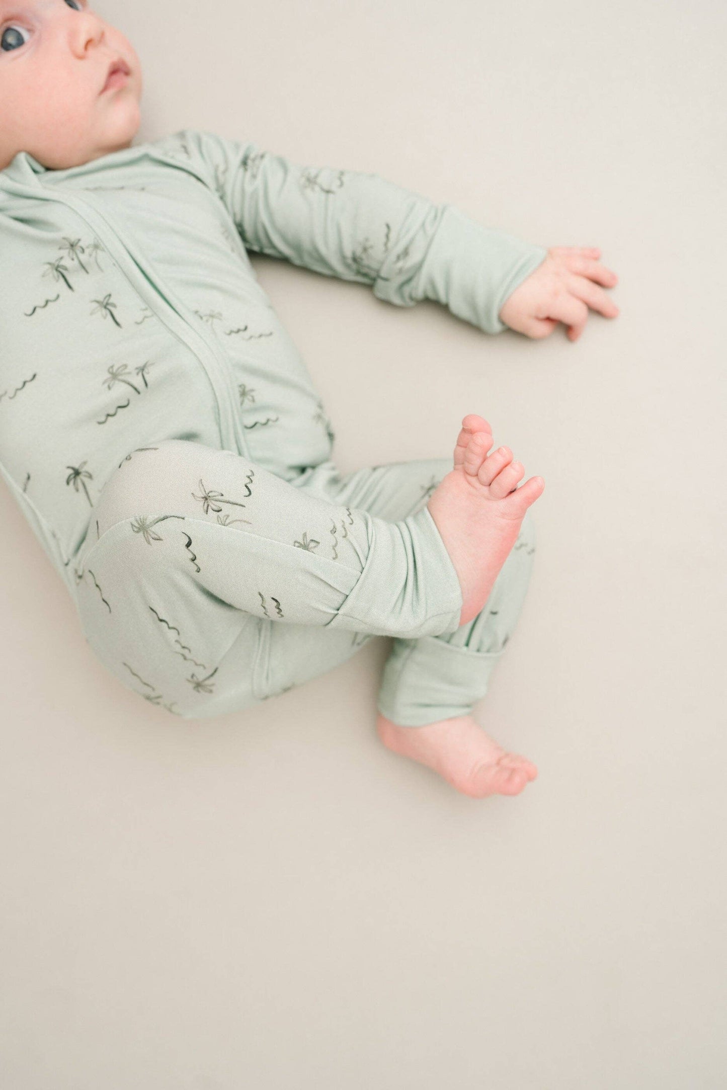 Baby in Palm Breeze Bamboo Sleeper with fold-over mittens covering hands for warmth and protection.