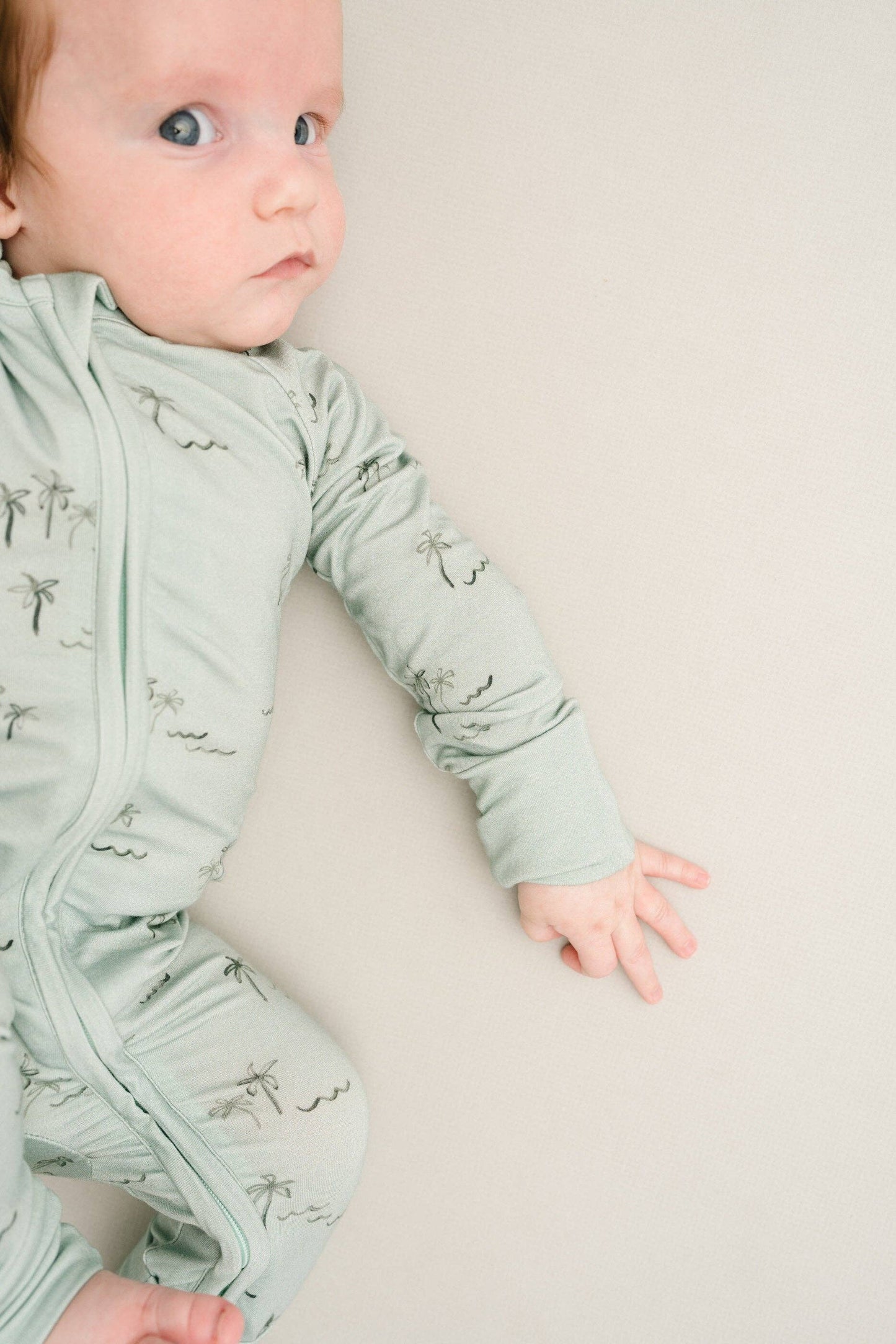 Baby lying on side in Palm Breeze Bamboo Sleeper, showing soft stretch and snug fit.