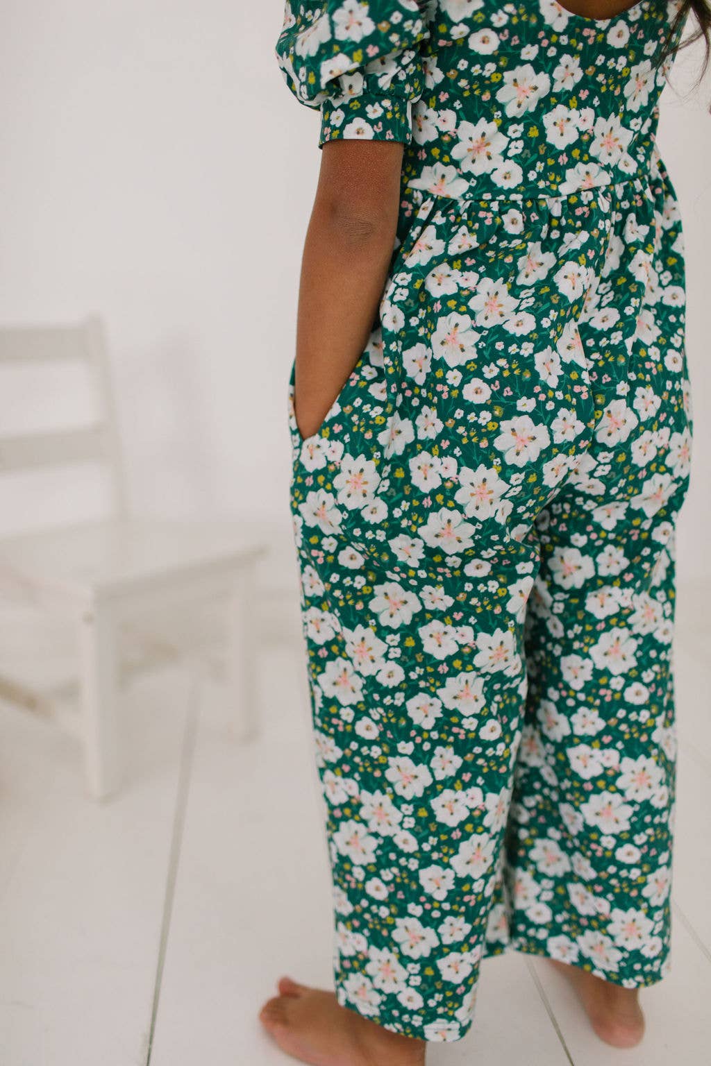 Back view of toddler model wearing the puff sleeve romper, highlighting the pockets and cropped wide-leg design.