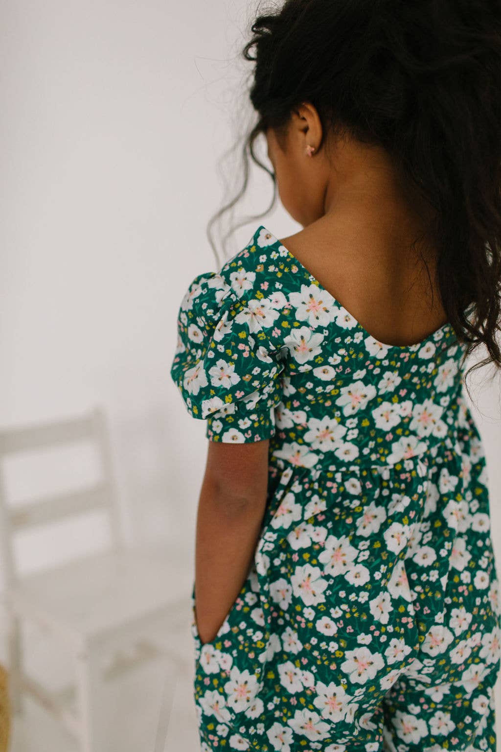 Toddler model showing the side pockets of the puff sleeve romper, perfect for playtime essentials.