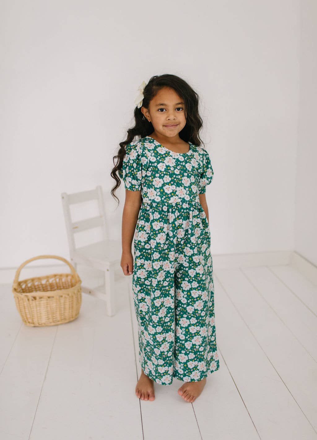 Toddler model standing in the puff sleeve romper, highlighting the playful wide-leg crop and quality of the soft fabric.