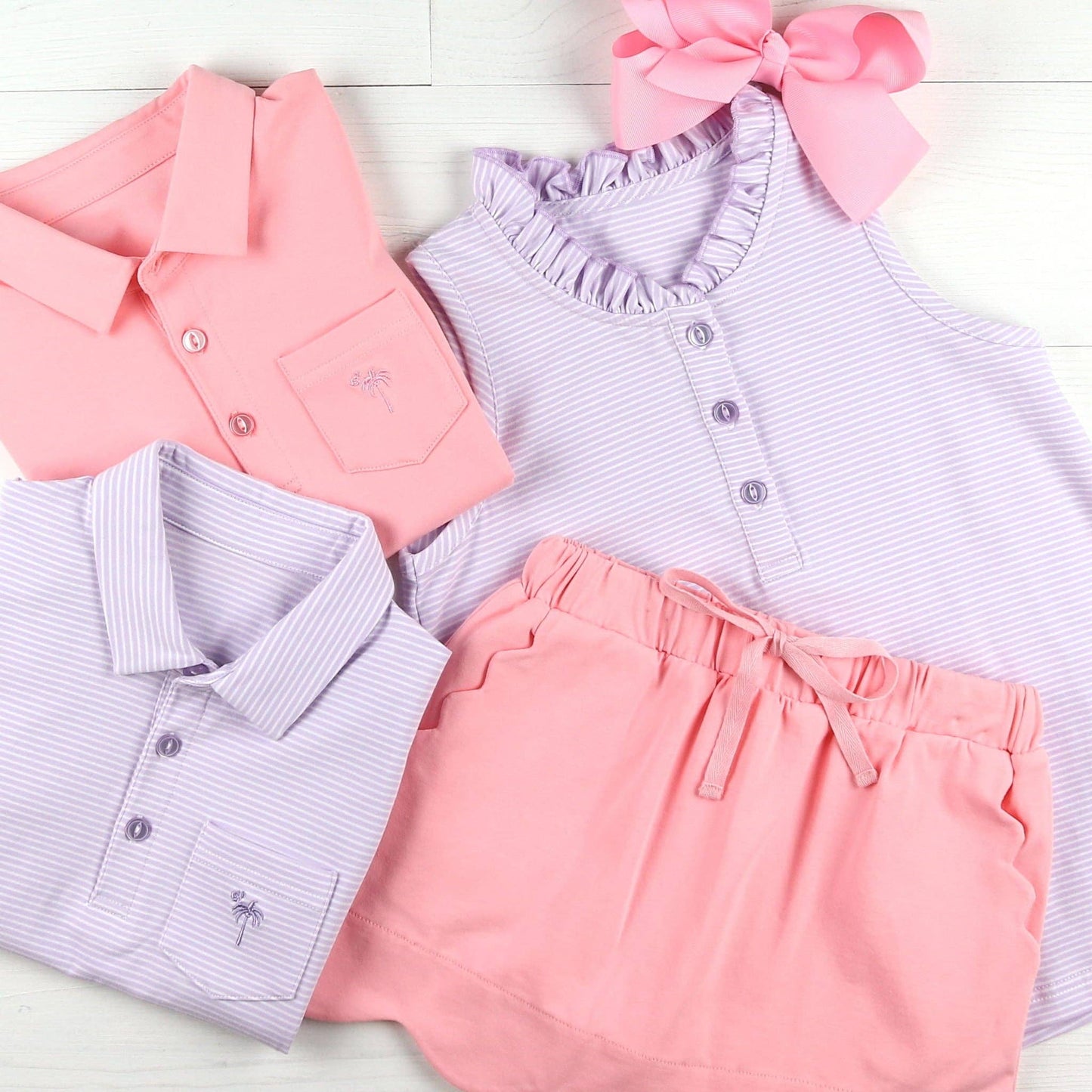 Flat lay of the Girls Ruffle Neck Polo paired with coordinating pieces, styled for mix-and-match versatility with skirts and shorts from the Serendipity collection.
