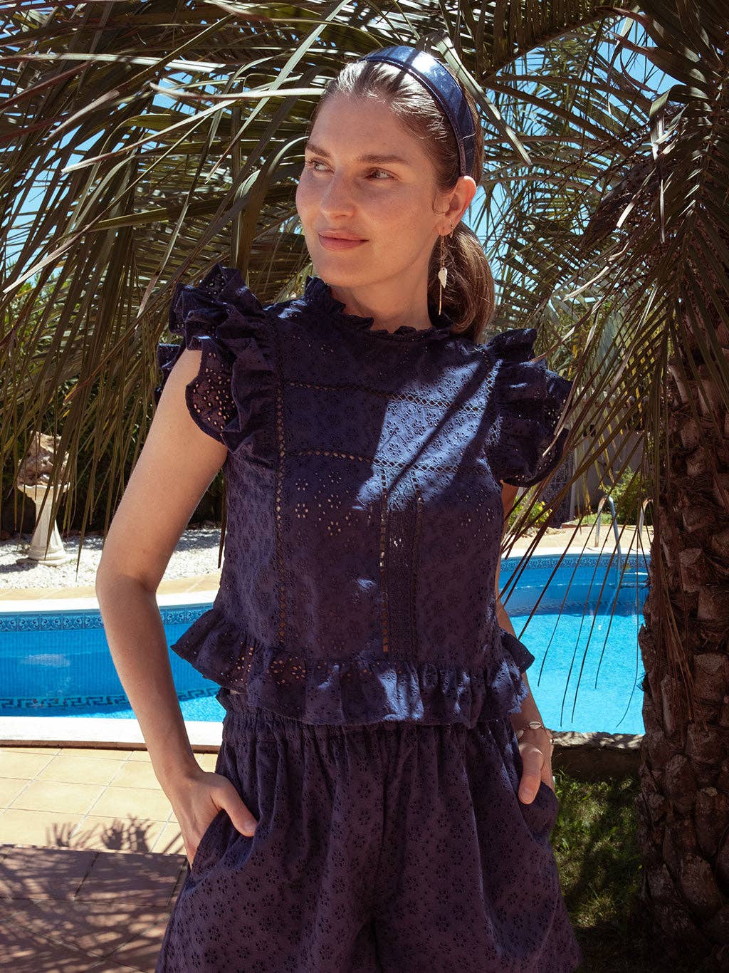 Sasha top styled with Olivia shorts in navy eyelet set, shown in front of a palm tree for a relaxed vacation look.