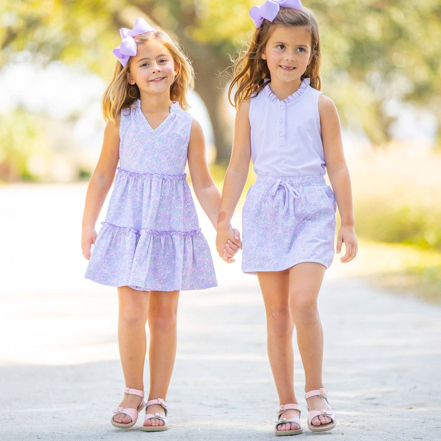 Outdoor image of model wearing the Girls Ruffle Neck Polo in St. Simons Stripe with a skirt, showing the polished yet playful style.