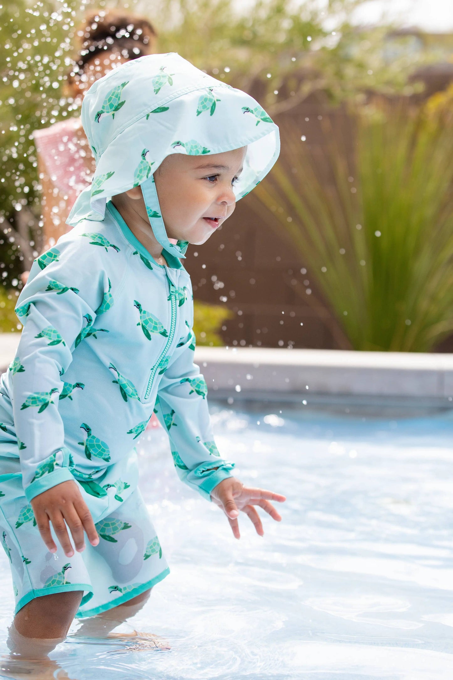 Toddler playing by the pool in Sea Turtles UPF bucket hat with chin strap and soft fabric design