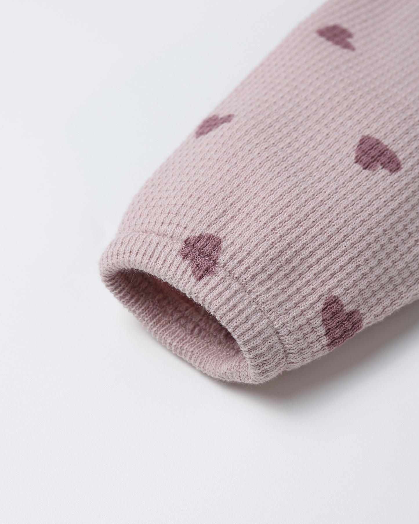 Close-up of heart print and hidden snap details on the Waffle Long Sleeve Jumpsuit by Quincy Mae.