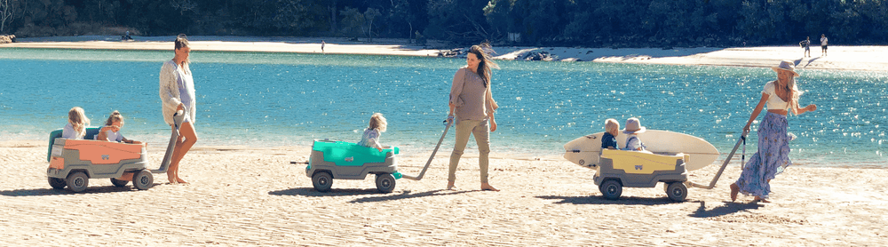 Burleigh Wagon carrying 3 children and a surfboard! Pulled by Dad carrying the umbrella in a bag over shoulder all while enjoying a day at the beach!