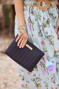 Navy Lemon Drop Citron clutch with woven texture, gold hardware, and a gold label, held by a woman wearing a animal print