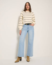 Spring Flare Jeans with Seam in light blue denim, high-waisted with a seam detail, paired with tan boots and a cream striped