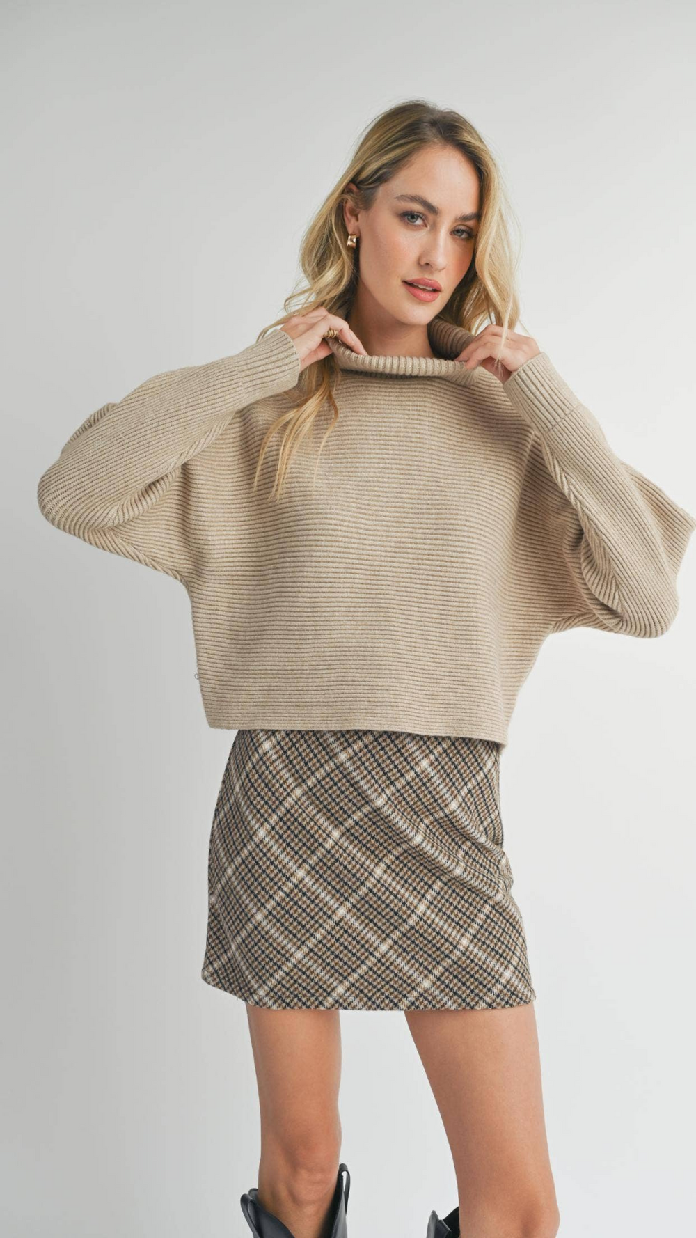 Close-up of the model’s outfit featuring the Anya Turtleneck Sweater, a skirt, and boots, emphasizing the sweater’s soft texture and stylish silhouette.