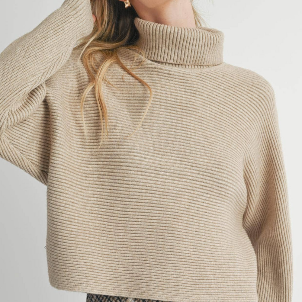 
                      
                        Close-up of the model’s outfit featuring the Anya Turtleneck Sweater, a skirt, and boots, emphasizing the sweater’s soft texture and stylish silhouette.
                      
                    