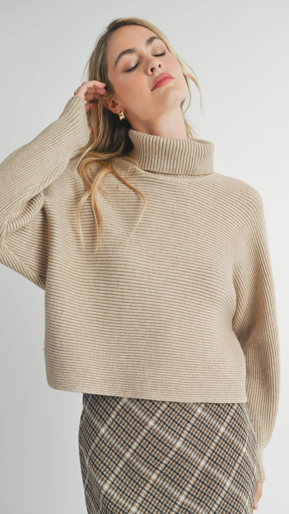 Close-up of the model’s outfit featuring the Anya Turtleneck Sweater, a skirt, and boots, emphasizing the sweater’s soft texture and stylish silhouette.