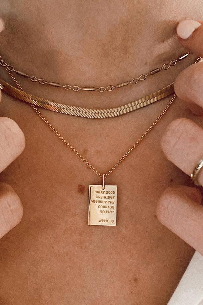 Wings Pendant Necklace featuring a rectangular gold pendant engraved with Atticus Poetry’s quote.