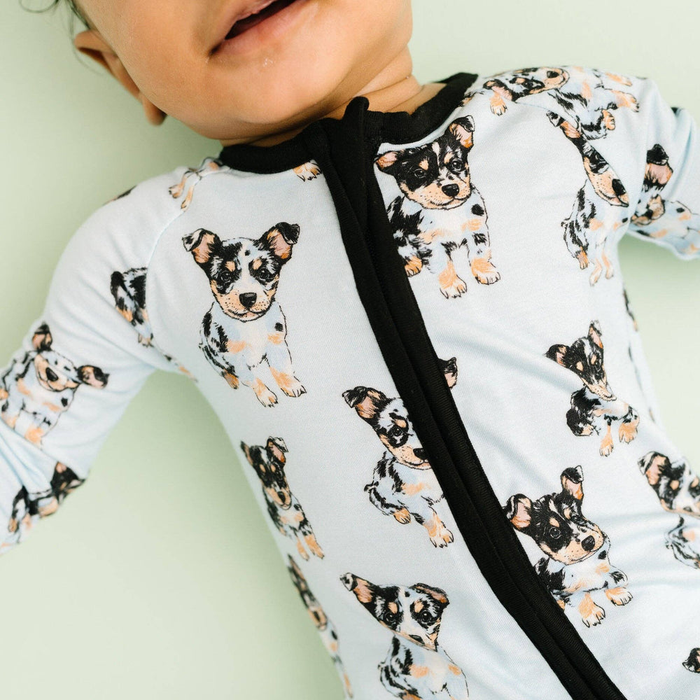 
                      
                        Close-up of a baby wearing a soft bamboo sleeper featuring a playful blue heeler print. The sleeper is made from organic bamboo fabric, known for its softness and breathability, keeping the baby cozy and comfortable. The design showcases adorable blue heeler dogs, adding a fun and charming touch to the sleeper. Perfect for any little one, this sleeper offers both comfort and style with its sustainable, eco-friendly material. Ideal for sleep or play, it’s a must-have in your baby’s wardrobe.
                      
                    