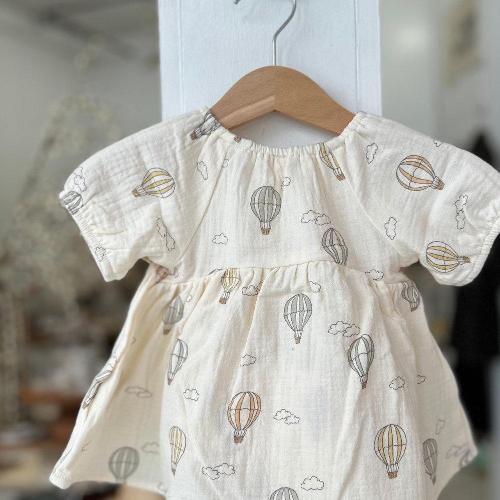 
                      
                        This dreamy dress features a whimsical hot air balloon print on a soft, neutral-toned fabric, perfect for adding a touch of adventure and charm to any occasion.
                      
                    