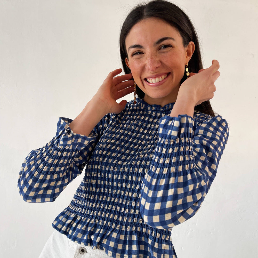 Elegant blue blouse with ruffle accents at the neckline, cuffs, and hem, perfect for women.