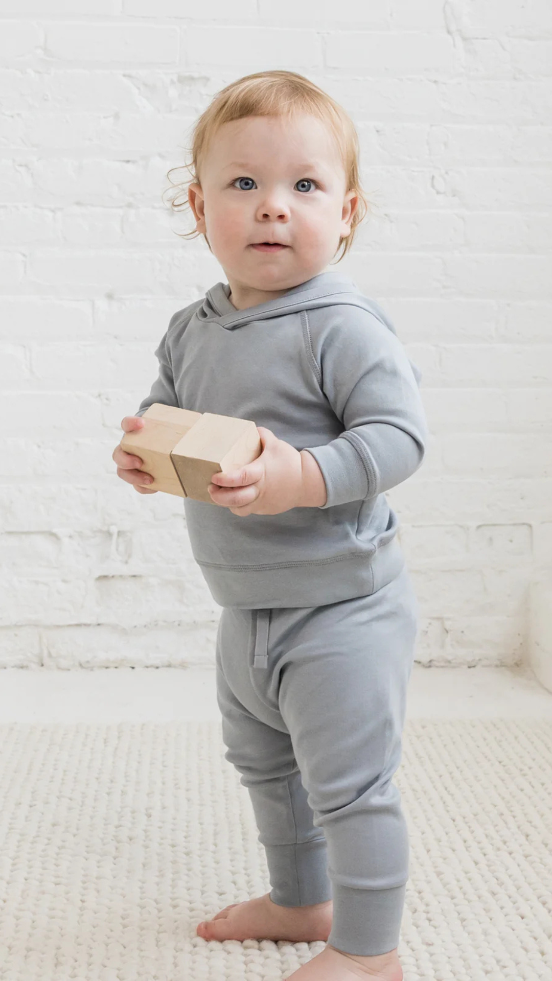 Toddler sporting all mist play outfit with joggers and hooded sweatshirt from Colored Organics, perfect for playing with blocks.