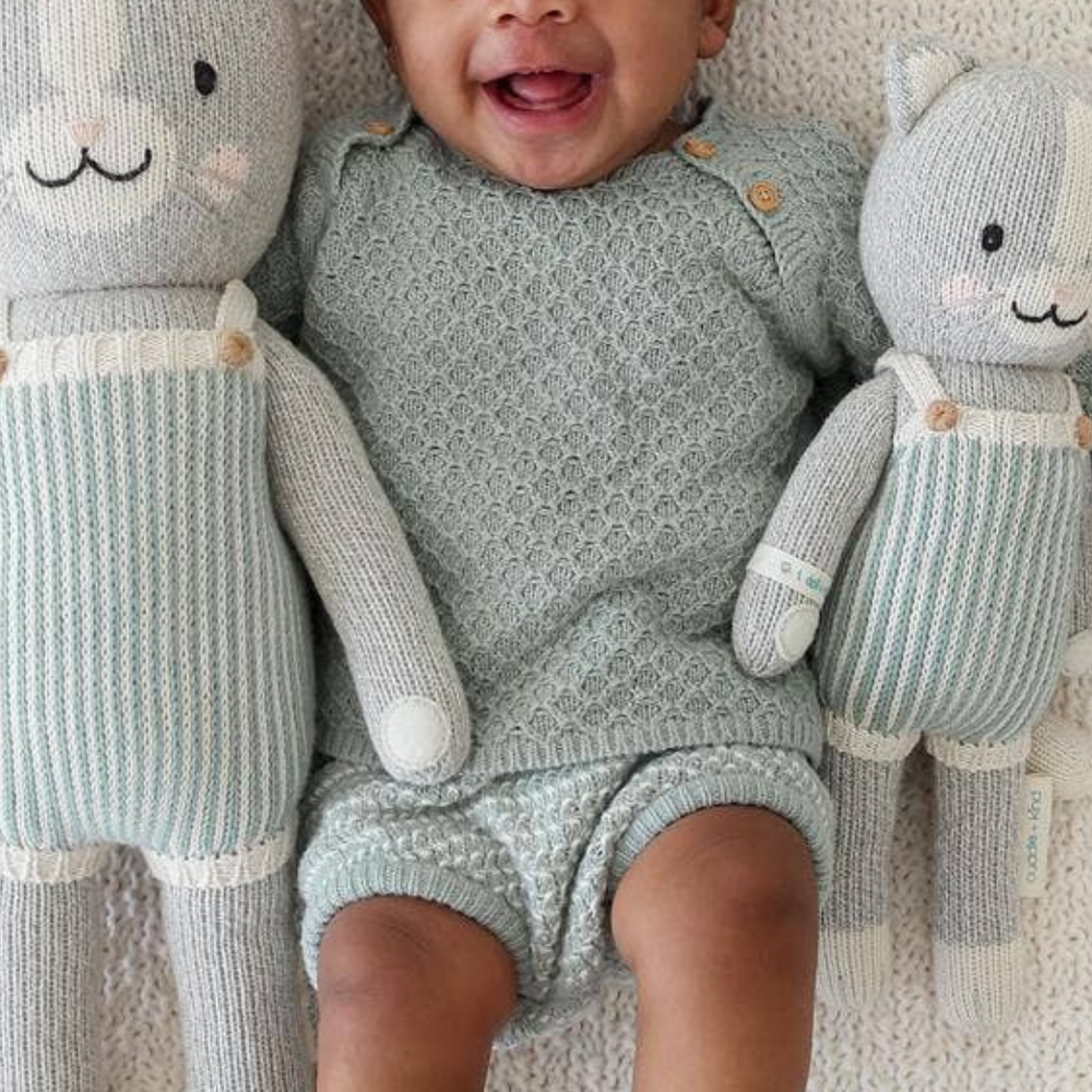 Happy baby holding Dylan the Kitten dolls in both Little (13”) and Regular (20”) sizes, showcasing the perfect cuddle companions for little ones.