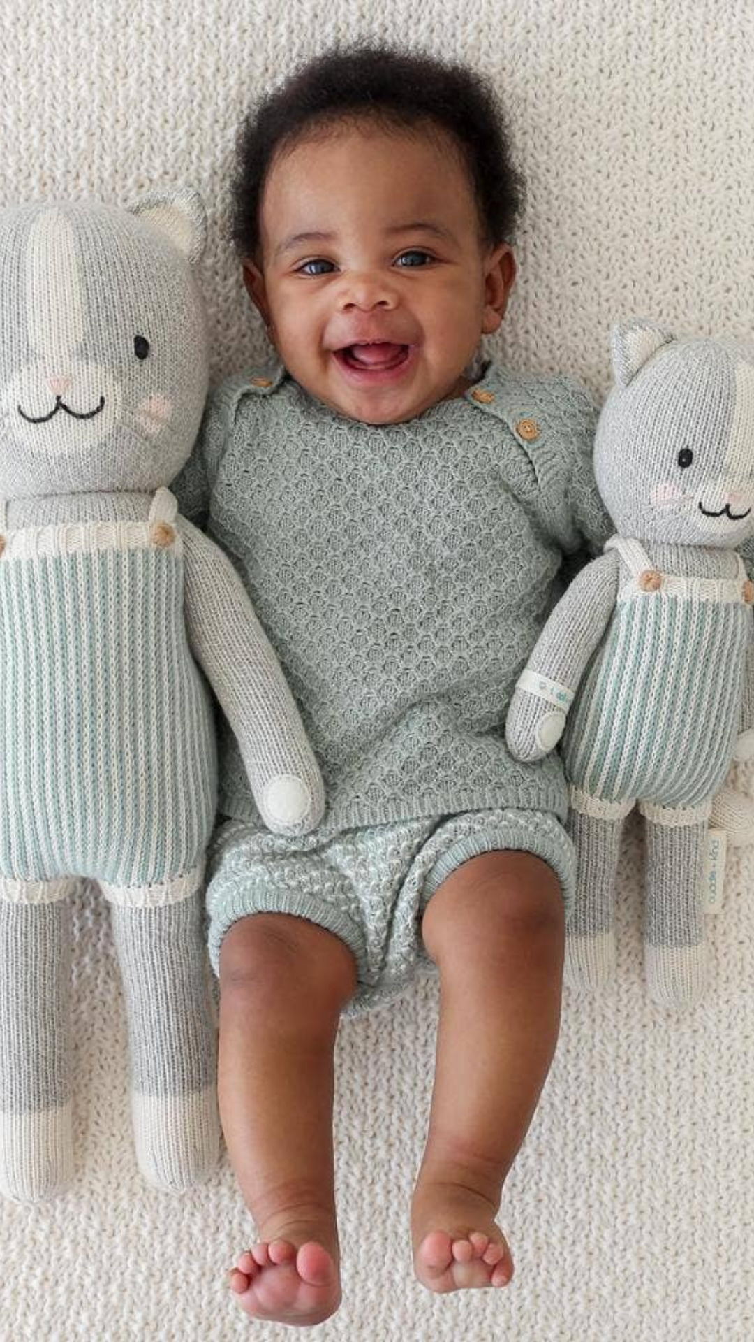 Happy baby holding Dylan the Kitten dolls in both Little (13”) and Regular (20”) sizes, showcasing the perfect cuddle companions for little ones.