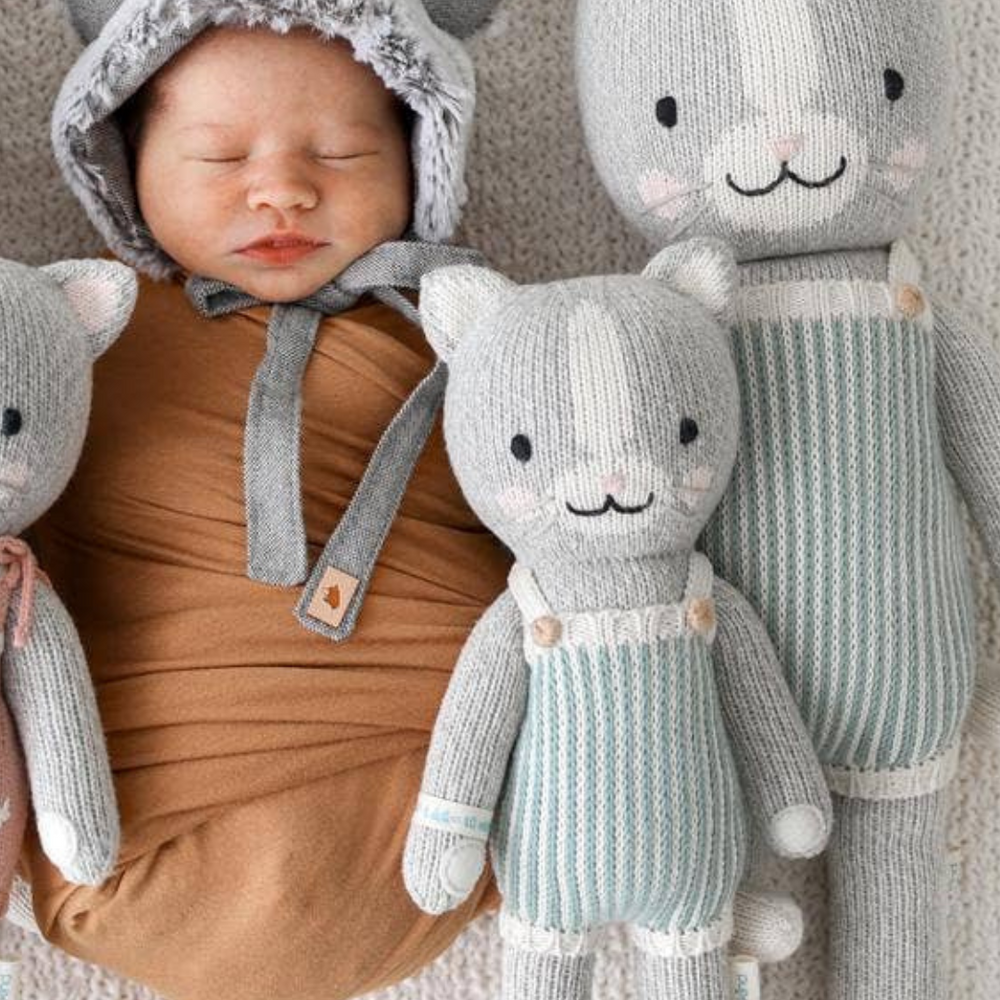 
                      
                        Swaddled baby lying beside both sizes of Dylan the Kitten, demonstrating the ideal cuddle doll for newborns and toddlers.
                      
                    