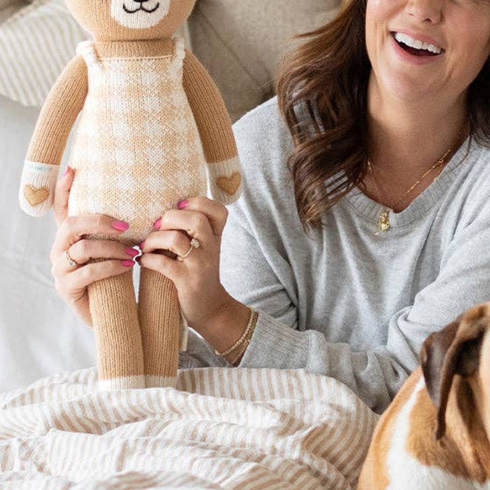 Jillian Harris lovingly holding the Hayden the Dog doll from her limited edition collection with Cuddle + Kind, showcasing the special design and craftsmanship.