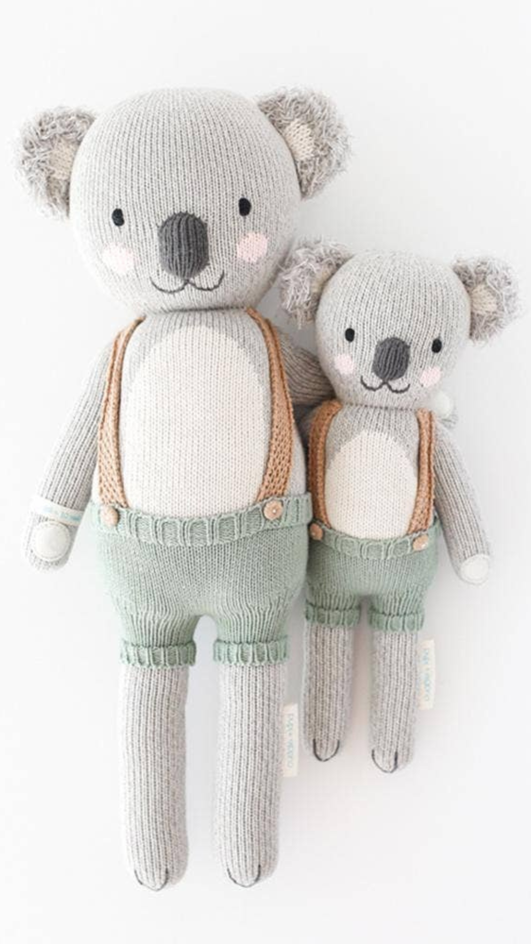 Flatlay of Quinn the Koala doll in Little (13”) and Regular (20”) sizes with soft colors, showcasing heirloom-quality hand-knit craftsmanship.