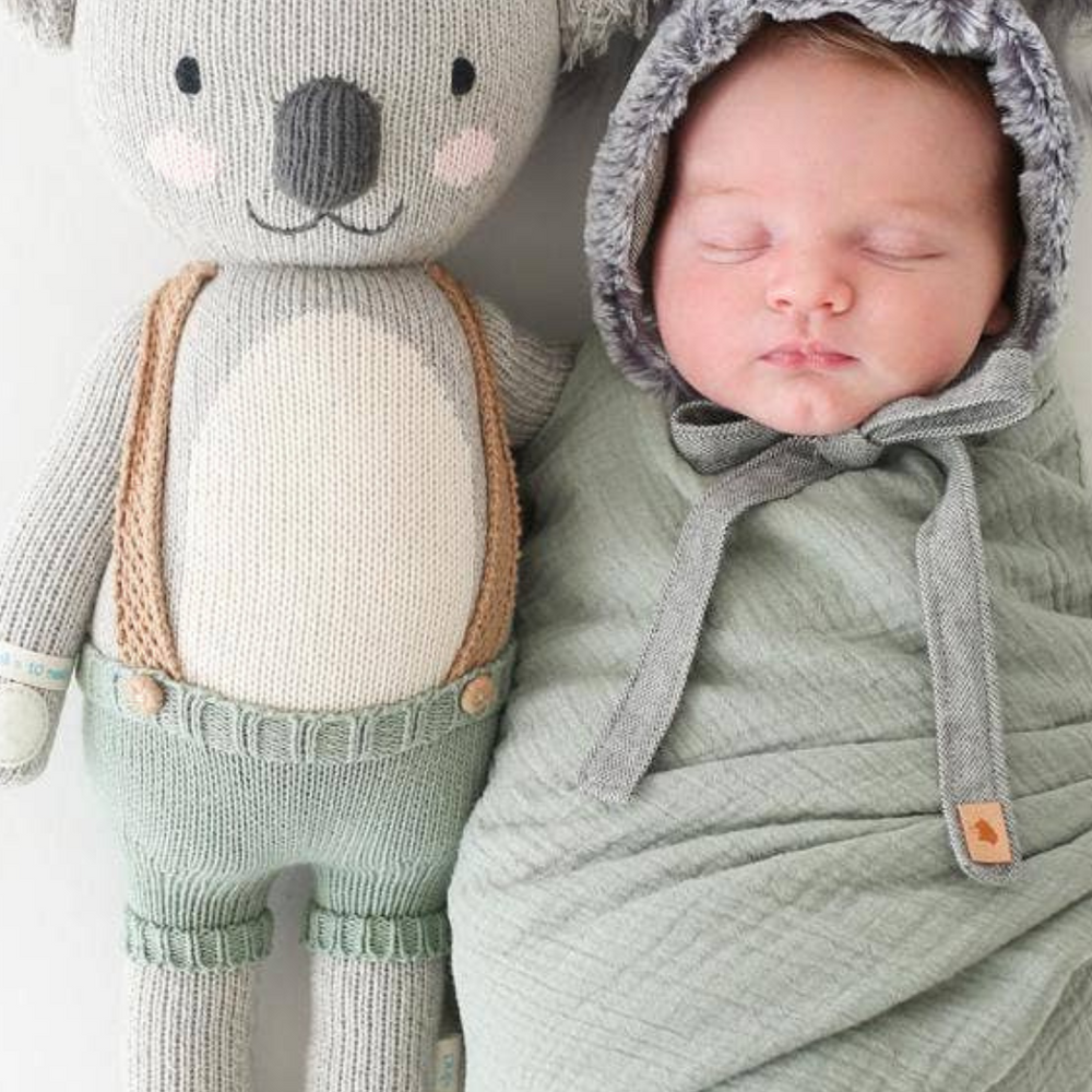 
                      
                        Quinn the Koala (20”) beside a swaddled infant in complementary colors, highlighting the doll’s perfect size for little ones.
                      
                    