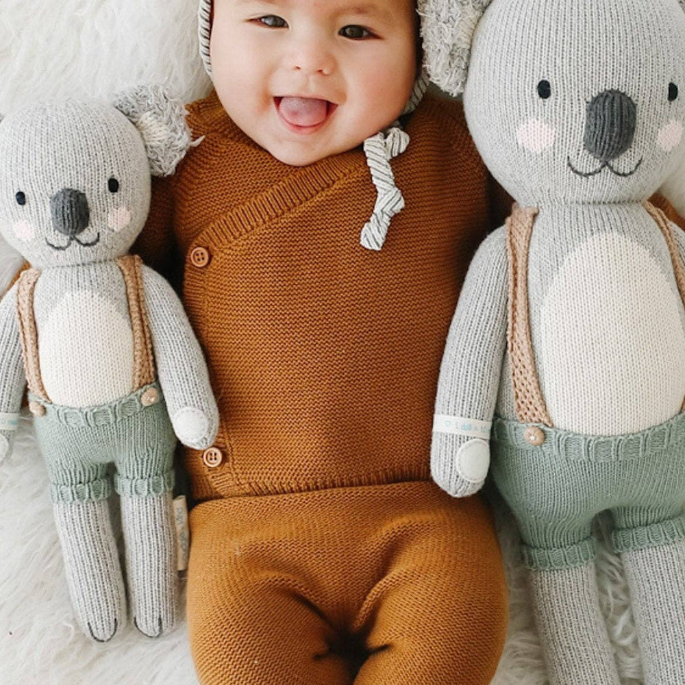 Happy baby nestled between both sizes of Quinn the Koala, illustrating the ideal cuddle buddy for newborns and toddlers.