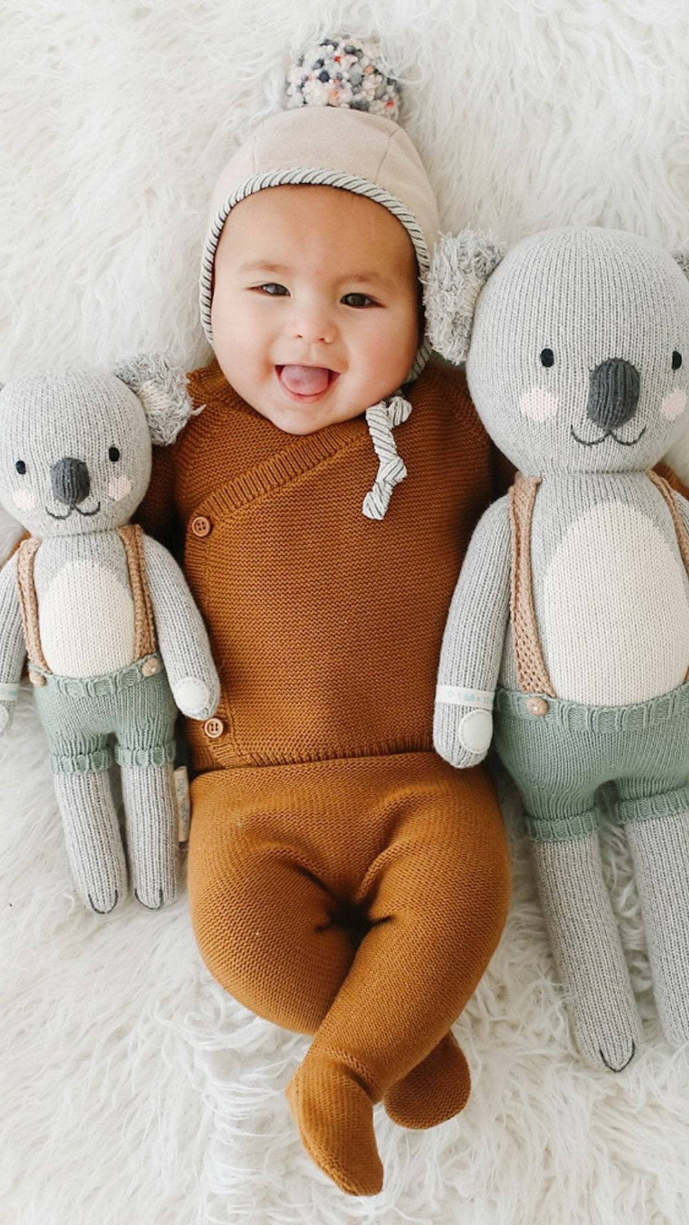 Happy baby nestled between both sizes of Quinn the Koala, illustrating the ideal cuddle buddy for newborns and toddlers.